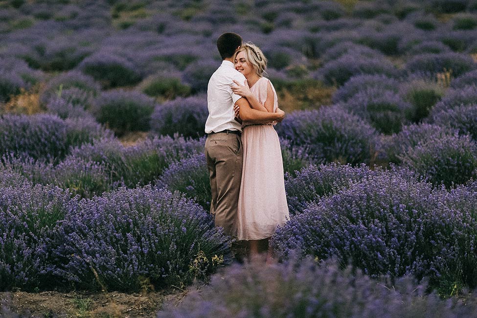 A couple hugs during their engagement photos in a lavender field.