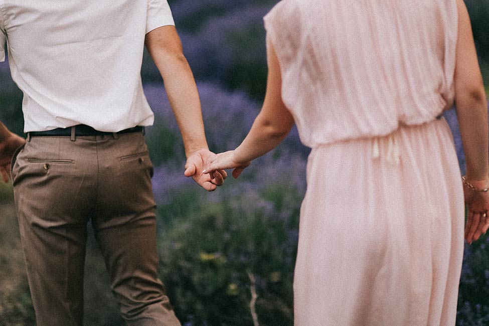 A wedding couple holding hands in a French lavender field.